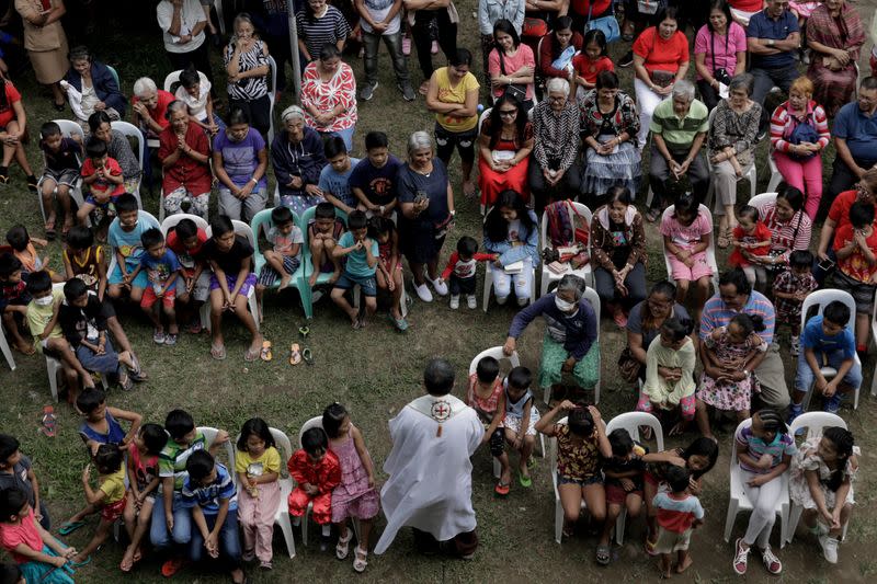 Residents displaced by the erupting Taal Volcano attend a Catholic mass in an evacuation center