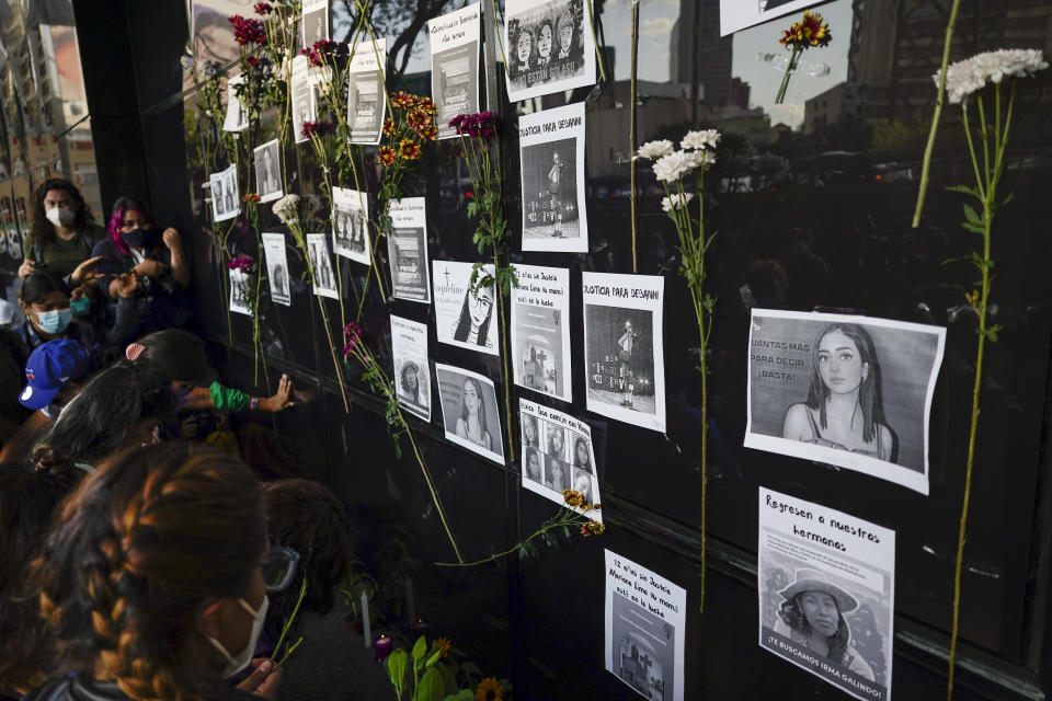 Flowers on the facade of the Attorney General's office surround images of Debanhi Escobar, right center, and other missing women, during a protest against femicide, in Mexico City, Friday, April 22, 2022. The protest was triggered after Escobar's decomposing body was recently found in a subterranean water tank at a motel when workers reported foul odors coming from the water holding tank. (AP Photo/Eduardo Verdugo)