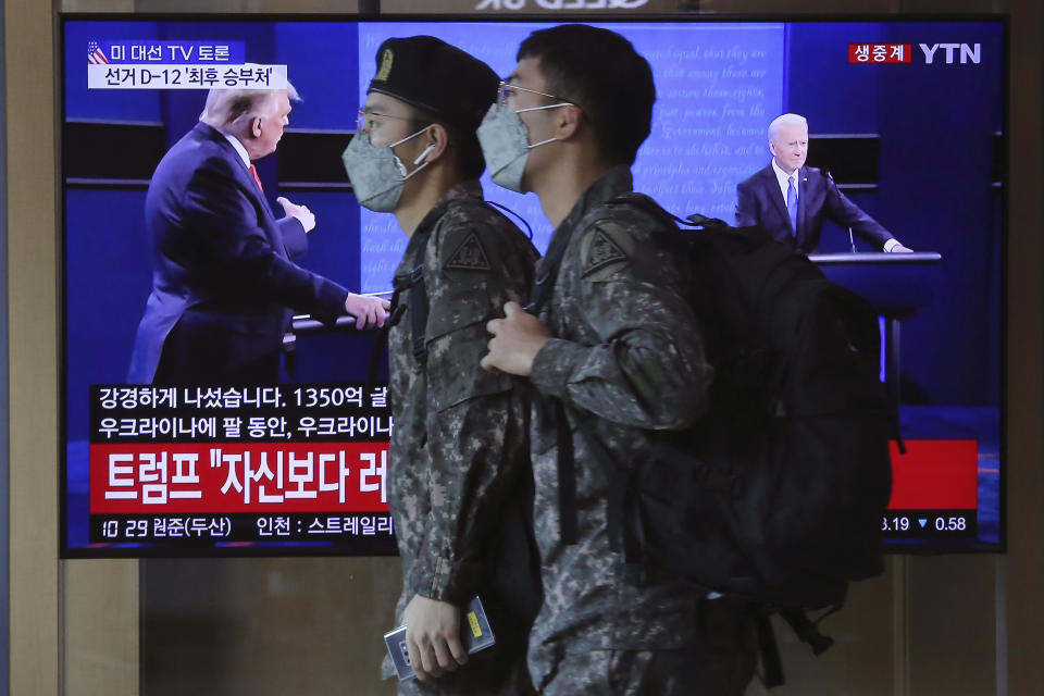 FILE - In this Oct. 23, 2020, file photo South Korean army soldiers pass by a TV screen showing a live broadcast of then-President Donald Trump, left, debating then-Democratic presidential candidate former Vice President Joe Biden, at the Seoul Railway Station in Seoul, South Korea. A new agreement with South Korea on sharing the cost of keeping U.S. troops on the Korean peninsula is early evidence that President Joe Biden is shifting America's approach to alliances in Asia and beyond. It shows he will cut allies a break to build unity in competition against China and Russia. (AP Photo/Ahn Young-joon, File)