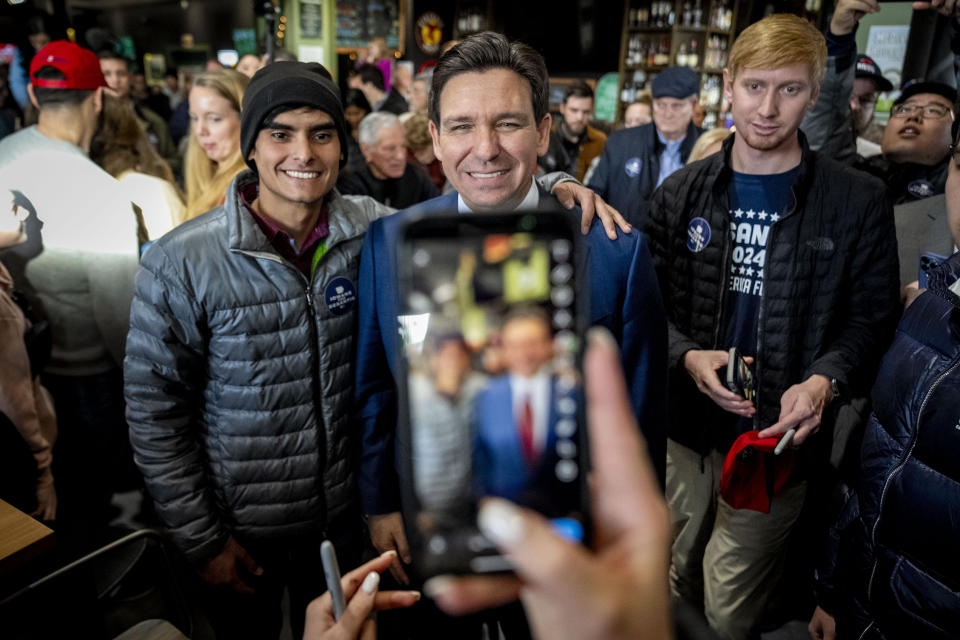 Republican presidential candidate Florida Gov. Ron DeSantis, center, takes a photo with a member of the audience at a rally at McDivot's Indoor Sports Pub in Grimes, Iowa, Sunday, Jan. 7, 2024. (AP Photo/Andrew Harnik)