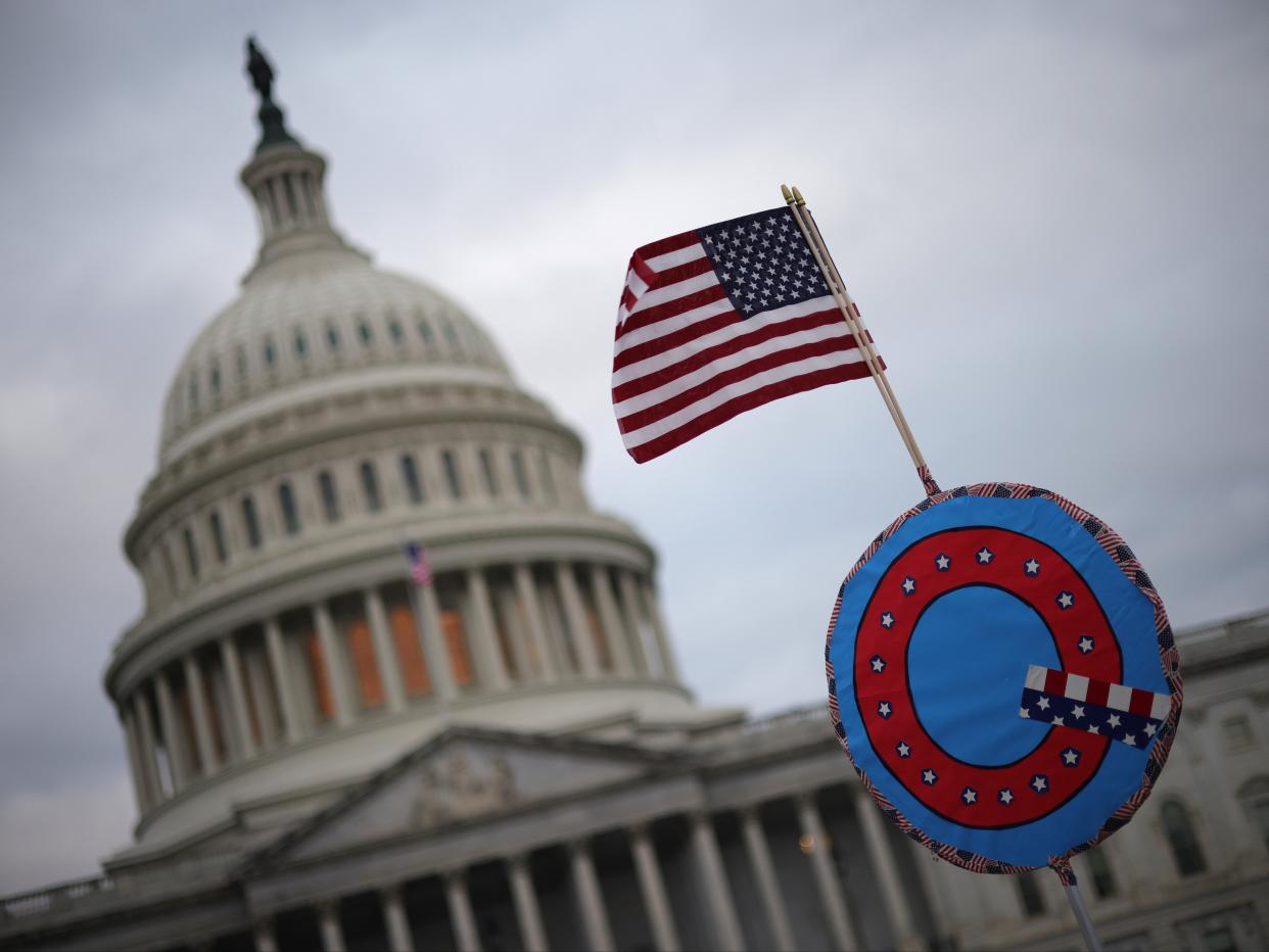 Los partidarios de Donald Trump enarbolan una bandera estadounidense con un símbolo del grupo QAnon mientras se reúnen frente al Capitolio de los Estados Unidos el 6 de enero de 2021 en Washington, DC ((Getty Images))