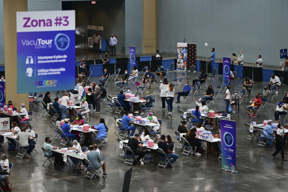 People come in for the first mass vaccination event carried out by the Department of Health and the Voces nonprofit organization, seeking to apply 10,000 Johnson and Johnson vaccines, at the Miramar Convention Center in San Juan, Puerto Rico, Wednesday, March 31, 2021. (AP Photo/Carlos Giusti)