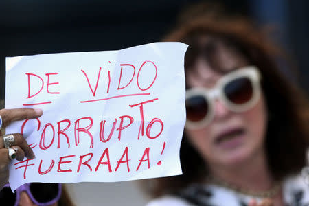 A woman holds a sign against former Planning Minister Julio De Vido outside the federal justice building where De Vido turned himself in to authorities, in Buenos Aires, Argentina October 25, 2017. The sign reads "Corrupt De Vido, go away". REUTERS/Marcos Brindicci