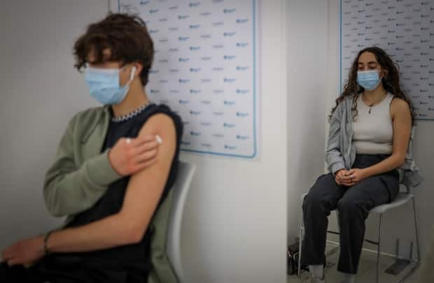 Hisham Arafat, 15, left, and his sister Maria Arafat, 17, receive their COVID-19 vaccine in Calgary last May. Currently, 75.2 per cent of eligible Albertans are fully vaccinated with two vaccine doses. (Leah Hennel/AHS - image credit)