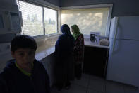 The wife, daughter and son of Abdul (not shown), who worked as a mechanic before he left Kabul, Afghanistan with his family about a month ago, stand, Thursday, Sept. 16, 2021, in the kitchen of the rental house the family has been provided as a place to stay in Seattle. The home is owned by Thuy Do, who was nine years old when her family arrived in the United States from Vietnam in the 1980s. Now Do and her husband have offered their vacant rental home to refugee resettlement groups to house newly arriving Afghans in need of a place to stay. (AP Photo/Ted S. Warren)