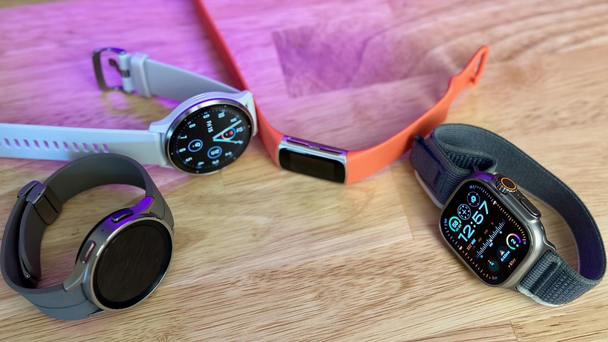  The Samsung Galaxy Watch 5 Pro (left), Garmin Venu 3 (middle-left), Fitbit Charge 6 (middle-right), and Apple Watch Ultra 2 (right) on a desk. 