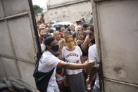 FILE - In this May 13, 2021 file photo, residents gather outside a gate for donated food from the Central Union of the Slums, known by its acronym CUFA, in the Jacarezinho favela of Rio de Janeiro, Brazil, amid the COVID-19 pandemic. As Brazil hurtles toward an official COVID-19 death toll of 500,000, President Jair Bolsonaro has waged a campaign to downplay the virus’s seriousness and keep the economy humming. (AP Photo/Silvia Izquierdo, File)