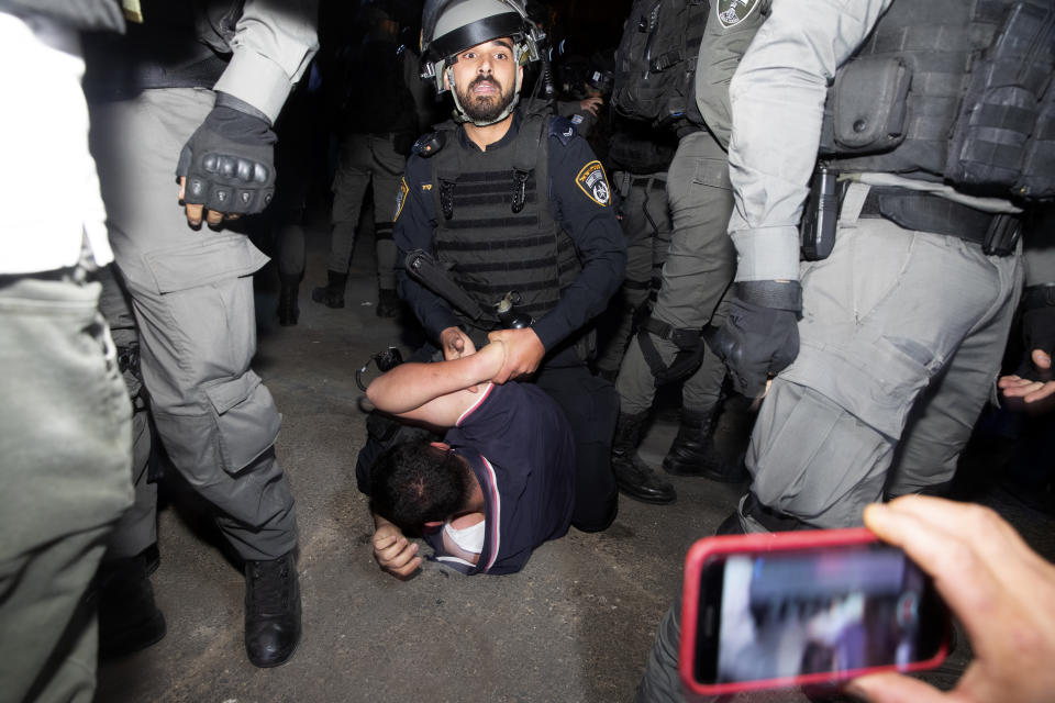 An Israeli police officer restrains a Palestinian during a protest on the eve of a court verdict that may forcibly evict Palestinian families from their homes in the Sheikh Jarrah neighborhood of Jerusalem, Wednesday, May 5, 2021. Several Palestinian families in Sheikh Jarrah have been embroiled in a long-running legal battle with Israeli settler groups trying to acquire property in the neighborhood near Jerusalem's famed Old City. (AP Photo/Maya Alleruzzo)