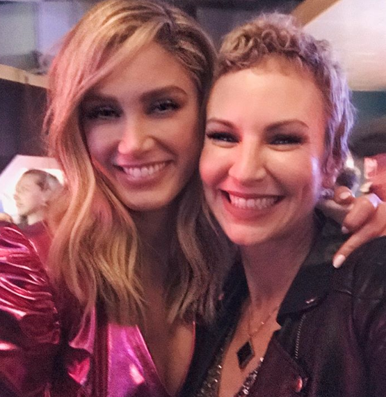 Delta Goodrem and Natasha Stuart hug and smile at the camera on the set of The Voice