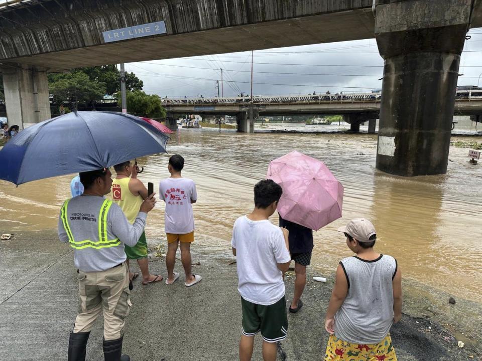 CORRECTS PHOTOGRAPHER'S LAST NAME TO CALUPITAN - Residents watch the Marikina river as it floods from monsoon rains worsened by offshore typhoon Gaemi on Wednesday, July 24, 2024, near Manila, Philippines. (AP Photo/Joeal Calupitan)