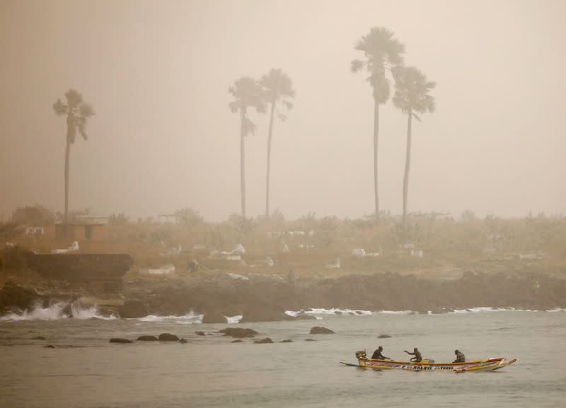 Fishermen are pictured on their pirogue as dust carried by winds from the Sahara Desert shrouds Dakar