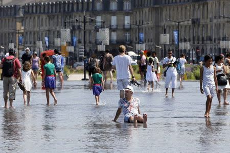 People cool off from the heat at the Miroir d'Eau (Mirror of Water), a public art piece on the quay of the Garonne river, during a warm summer day in Bordeaux, southwestern France, June 30, 2015. REUTERS/Regis Duvignau