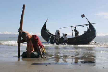 A woman collapses from exhaustion as Rohingya refugees arrive by a wooden boat from Myanmar to the shore of Shah Porir Dwip, in Teknaf, near Cox's Bazar in Bangladesh, October 1, 2017. REUTERS/Mohammad Ponir Hossain