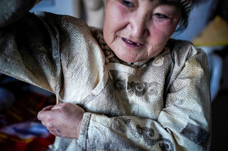 You Wenfeng, 68, an ethnic Hezhen woman poses with her fishskin clothes at her studio in Tongjiang