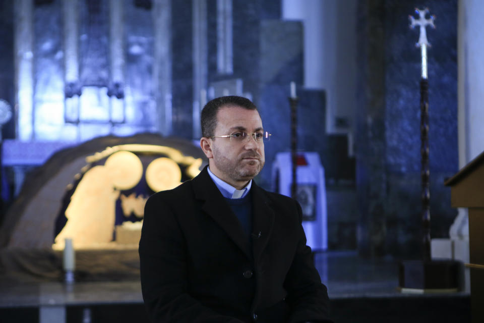 In this Jan. 18, 2019 photo, Catholic priest Behnam Benoka speaks to The Associated Press at the St. George Parish in Bartella, Iraq. Benoka claimed that the Christian community is being pushed out by the Shabak, a Shiite Muslim ethnic group who dominate the militias that now run Bartella. Two years after Bartella was liberated from IS, fewer than a third of its 3,800 Christian families have come back. (AP Photo/Fay Abuelgasim)