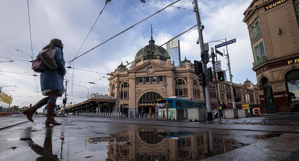 A woman walks through a deserted Melbourne CBD while wearing a mask. Source: AAP