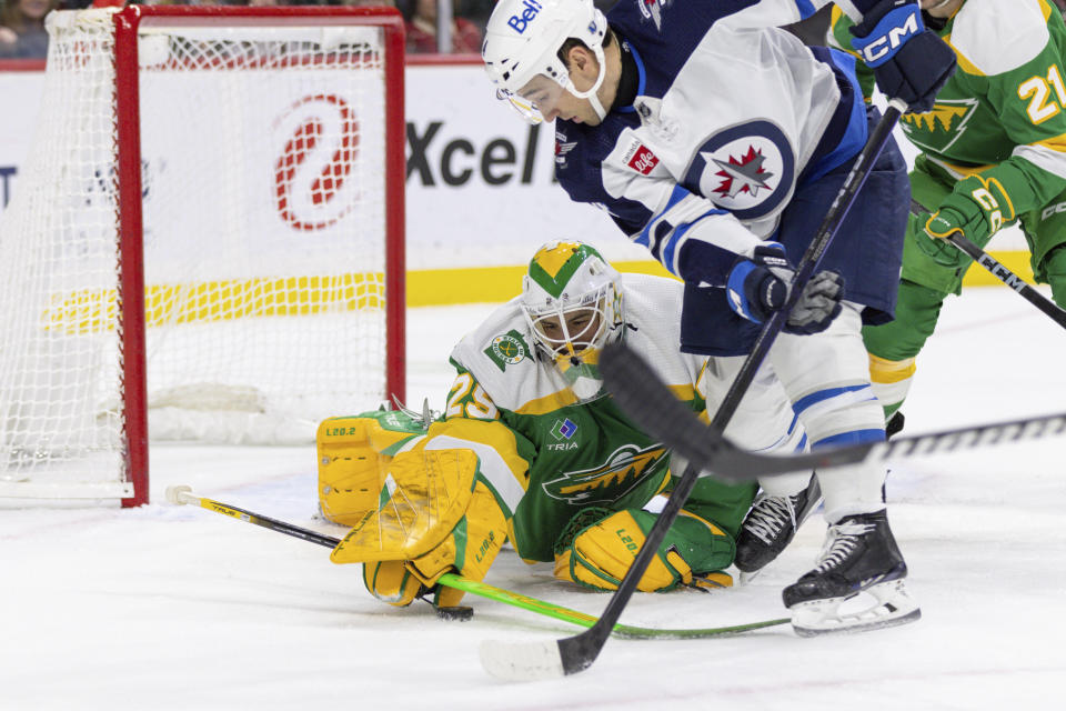 Minnesota Wild goaltender Marc-Andre Fleury, left, makes a save on a shot from Winnipeg Jets defenseman Neal Pionk, right, during the second period of an NHL hockey game Sunday, Dec. 31, 2023, in St. Paul, Minn. (AP Photo/Bailey Hillesheim)