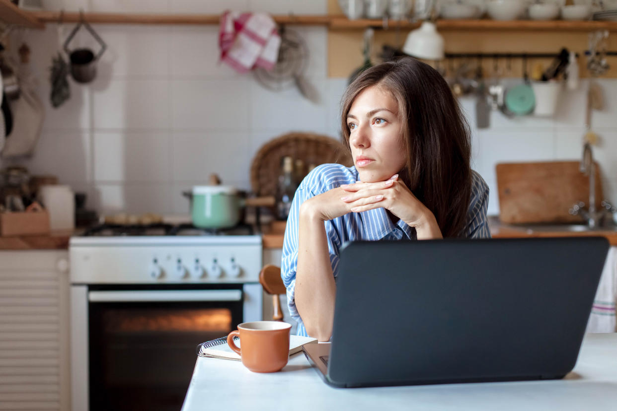 Working from home office. Upset woman using laptop and Internet. Freelancer workplace at kitchen table. Remote female business and career, stress in social distancing, self-isolation. Lifestyle moment