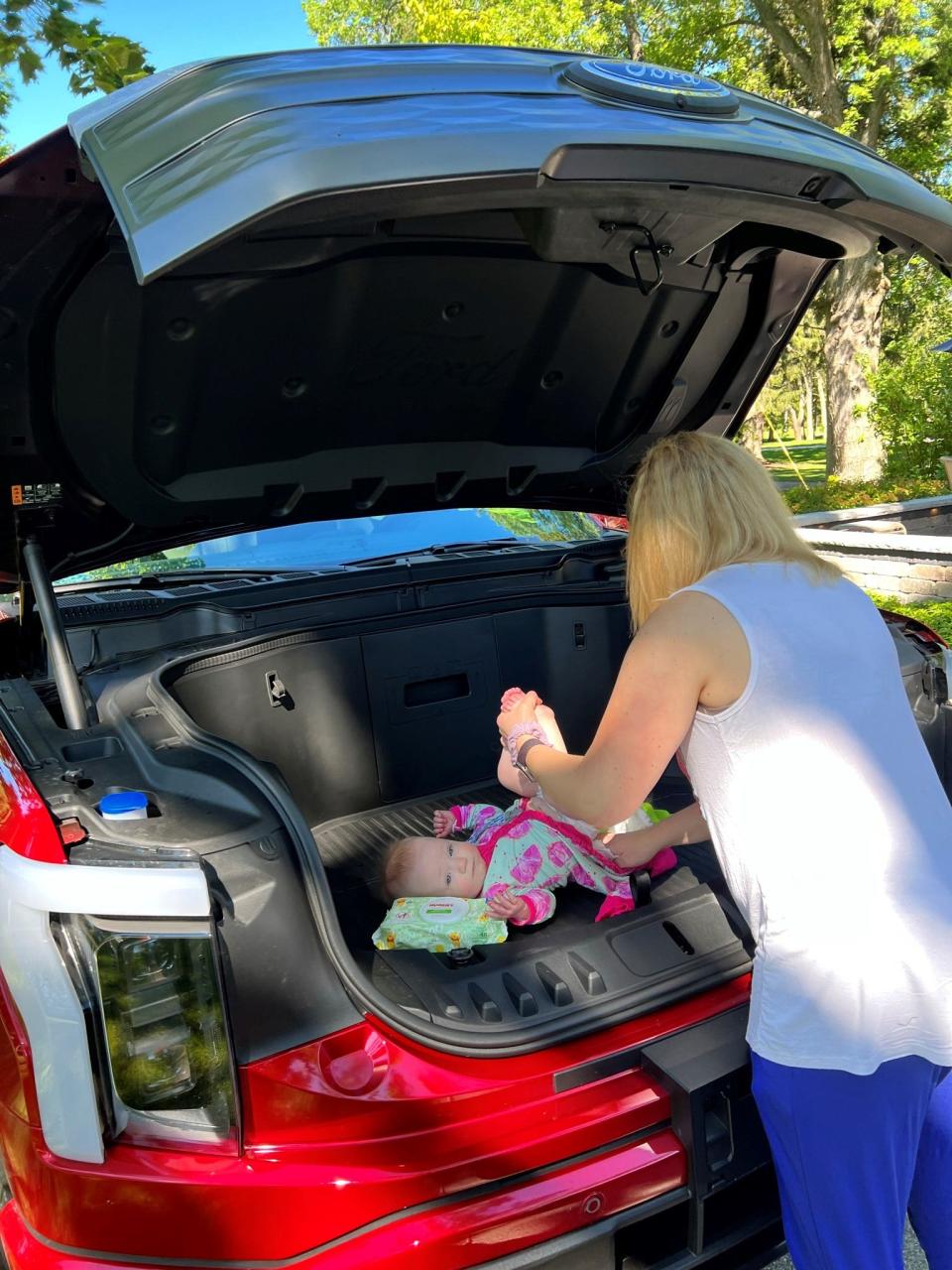 Emily Jaehnert of Richland, Washington changes her little MacKenzie in the front trunk of her Ford F-150 Lightning in August 2022.