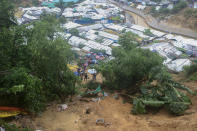 Rohingya refugees and others hold umbrellas as they search for survivors after a landslide triggered by heavy rains in a camp at Ukhiya in Cox's Bazar district, Bangladesh, Tuesday, July 27, 2021. (AP Photo/ Shafiqur Rahman)