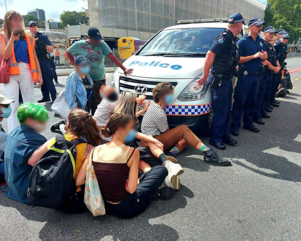 Protesters seen blocking a police van outside the Brisbane WatchHouse. 