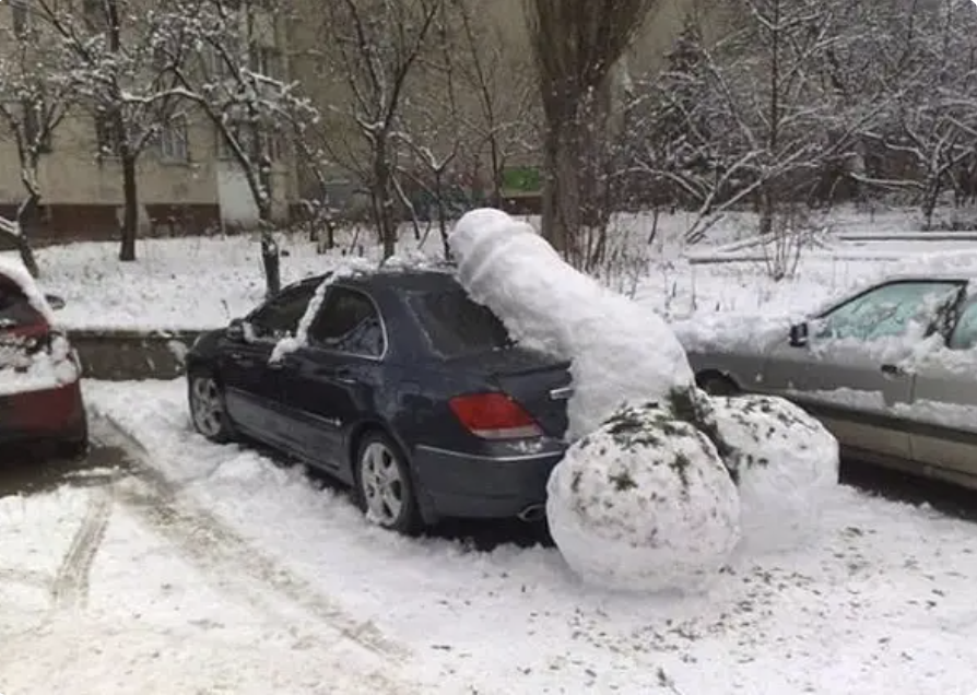 Snow in the shape of a penis and scrotum left on the back of a car in a parking space