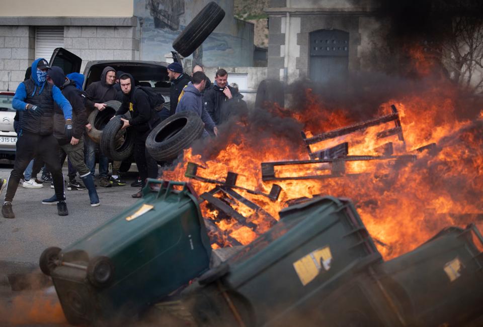 A protester throws tires onto a bonfire 