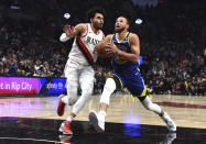 Golden State Warriors guard Stephen Curry, right, drives to the basket against Portland Trail Blazers forward Justin Minaya, left, during the first half of an NBA basketball game in Portland, Ore., Thursday, April 11, 2024. (AP Photo/Steve Dykes)