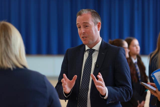 Paul Givan gestures with his hands while talking to another person