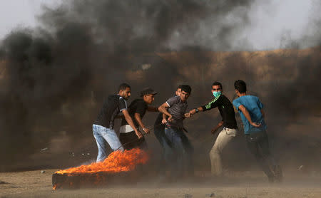 Palestinian demonstrators drag a burning tire during a protest demanding the right to return to their homeland, at the Israel-Gaza border in the southern Gaza Strip May 25, 2018. REUTERS/Ibraheem Abu Mustafa