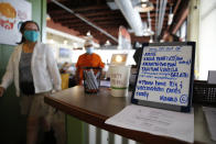 Customers walk past a sign reminding people to have their vaccination cards ready at Highway Inn restaurant in Honolulu on Monday, Oct. 25, 2021. To comply with local mandates, the restaurant requires all indoor diners to show proof of vaccination or have a recent negative test result before being seated. (AP Photo/Caleb Jones)