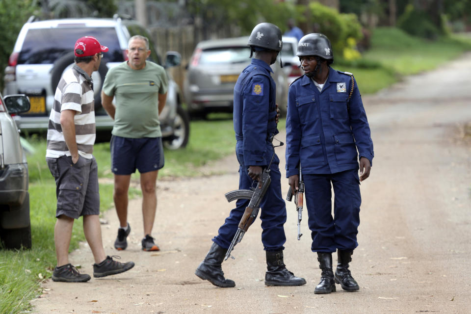 Neighbours watch as armed police surround the residence of Evan Mawarire, an activist and pastor who helped mobilize people to protest against the hike in fuel prices, following his arrest in Harare, Zimbabwe, Wednesday, Jan. 16, 2019. Mawarire was arrested Wednesday for allegedly inciting violence in the protests against the government's increase in fuel prices. (AP Photo/Tsvangirayi Mukwazhi)