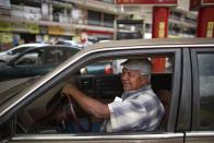 In this Oct. 8, 2019 photo, motorist Carlos Ortega waits as his car is filled up with gasoline by an attendant, who he paid in cash instead of bartering, at a gas station in San Antonio de los Altos on the outskirts of Caracas, Venezuela. Motorists in socialist Venezuela have long enjoyed the world’s cheapest gasoline, with fuel so heavily subsidized that a full tank these days costs a tiny fraction of a U.S. penny. (AP Photo/Ariana Cubillos)