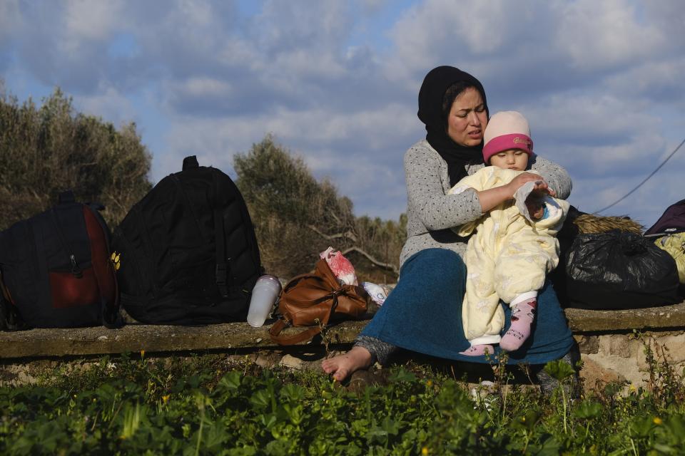 A migrant woman who arrived yesterday to Greece from Turkey, tries to warm her baby at the village of Skala Sikaminias, on the Greek island of Lesbos on Friday, March 6, 2020. Thousands of refugees and other asylum-seekers have tried to enter Greece from the land and sea in the week since Turkey declared its previously guarded gateways to Europe open. (AP Photo/Alexandros Michailidis)