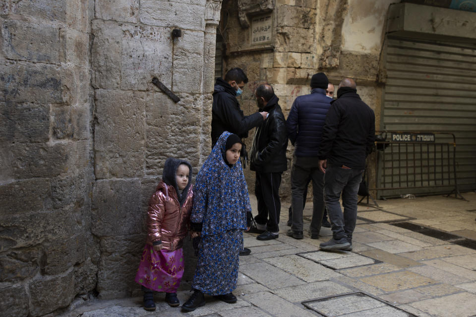 A girl wearing a head-to-toe Islamic garment stands with her sister at a police checkpoint as worshippers enter the Al Aqsa Mosque compound for Friday prayers in the Old City of Jerusalem, Friday, Jan. 22, 2021. Many people prayed outside the gates of the Old City, due to coronavirus restrictions. (AP Photo/Maya Alleruzzo)