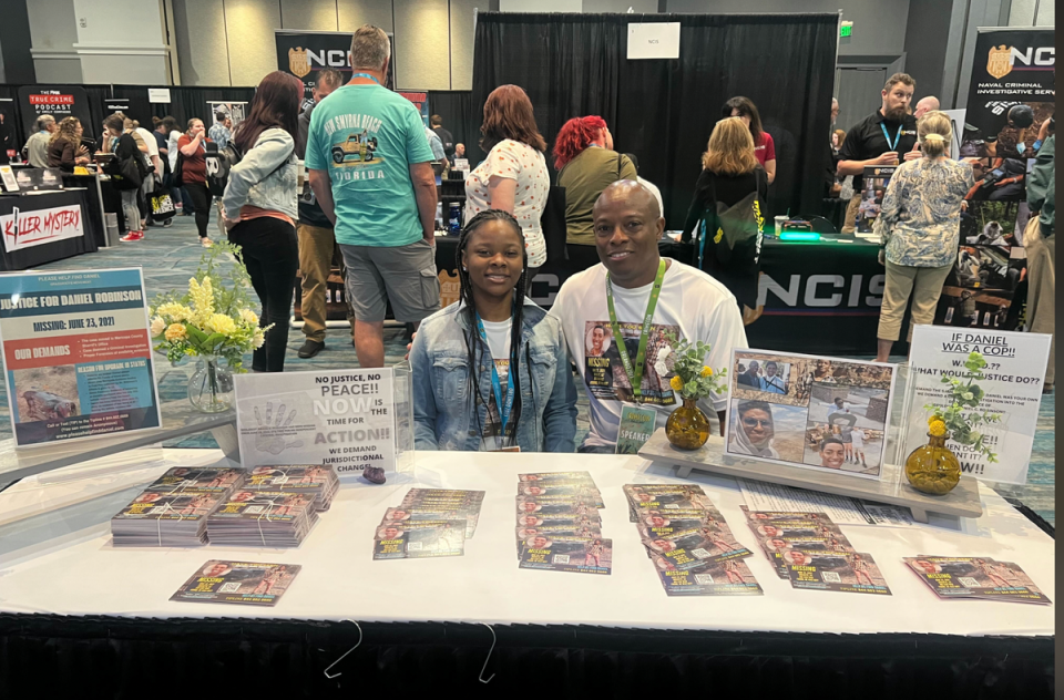 David Robinson and his daughter pass out fliers at CrimeCon 2023 in Orlando, Florida (Andrea Cavallier for The Independent)