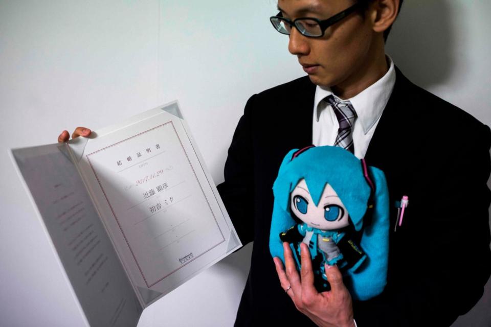 Mr Kondo and Miku display their marriage papers, drawn up by Gatebox. (AFP/Getty Images)