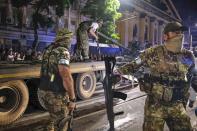 FILE - Members of the Wagner Group military company guard an area as other load their tank onto a truck on a street in Rostov-on-Don, Russia, on June 24, 2023, prior to leaving an area at the headquarters of the Russian Southern Military District. (Vasily Deryugin, Kommersant Publishing House via AP, File)