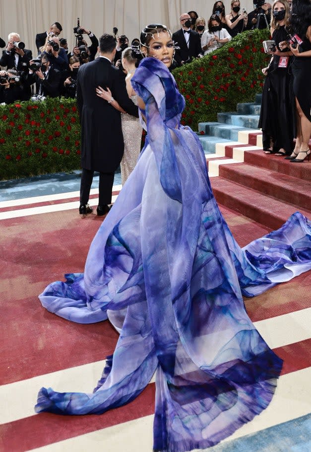 Teyana Taylor standing on the re carpet in a flowy tie-dyed gown