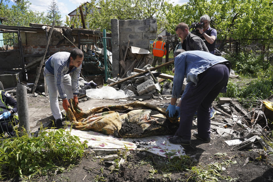 Police and volunteers exhume the body of a civilian killed by Russian shelling in the village of Malaya Rohan, on the outskirts of Kharkiv, Monday, May 16, 2022. (AP Photo/Andrii Marienko)