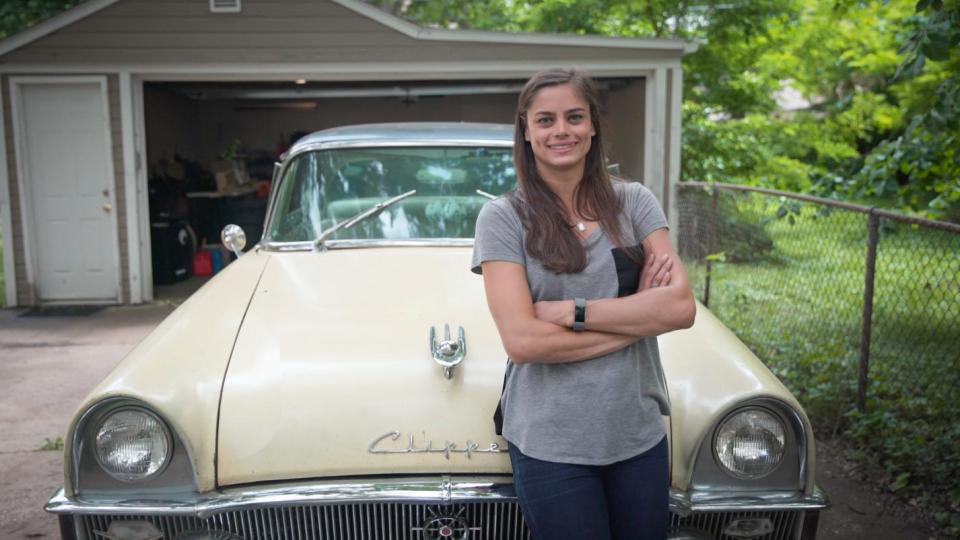Alex Archer and the 1955 Packard Clipper she is restoring in her home garage.