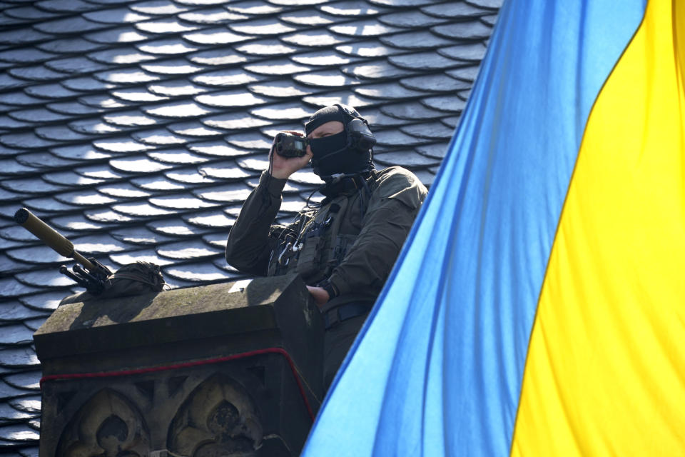 A sharpshooter looks out from a roof ahead of a ceremony to award the International Charlemagne Prize in Aachen, Germany, Sunday, May 14, 2023. Ukraine's President Volodymyr Zelenskyy and the people of Ukraine are due to receive the International Charlemagne Prize on Sunday for contributions to European unity. (AP Photo/Michael Probst)