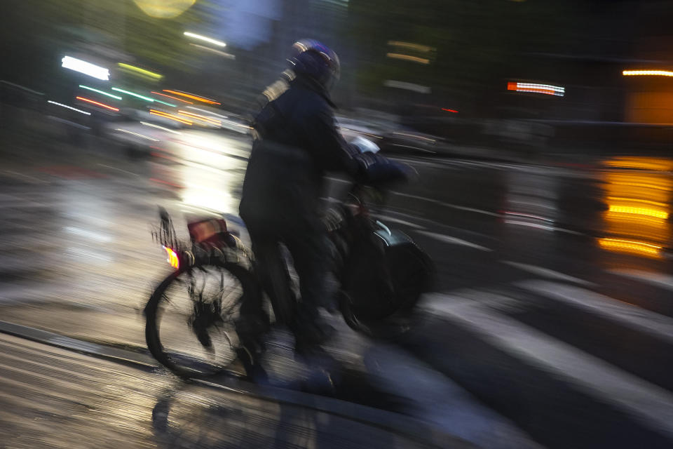 A food delivery worker rides in the night along Brooklyn's Bedford Avenue, Friday, April 28, 2023, in New York. Attacks which occurred in Florida last month sent ripples of fear among some app-based delivery workers, who have long demanded better protection from companies whose safety policies they say are bettered geared toward customers than workers. (AP Photo/Bebeto Matthews)