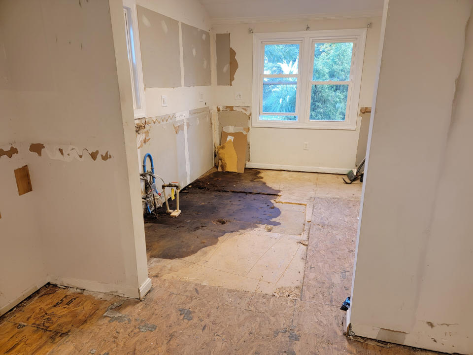 A damaged room with torn walls and flooring, suggesting renovation or damage repair in progress