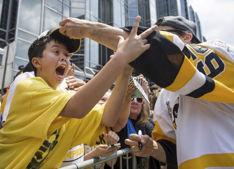Pittsburgh Penguins Marc-Andre Fleury places a hat on the head of a young fan during the team’s Stanley Cup NHL hockey victory parade on Wednesday, June 14, 2017, in Pittsburgh.(Steph Chambers/Pittsburgh Post-Gazette via AP)