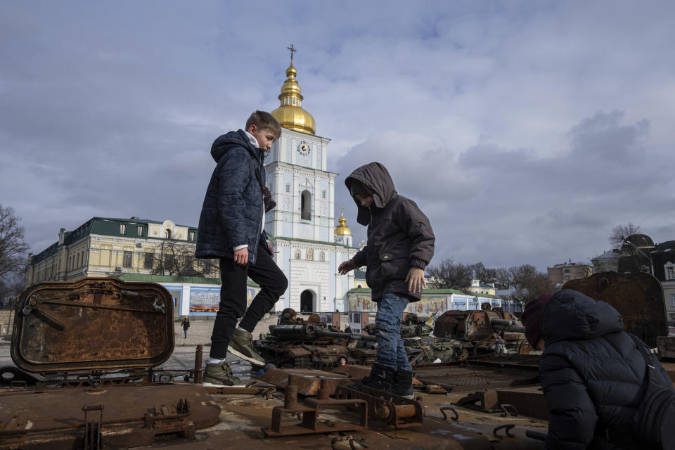 Children stand atop of a destroyed Russian vehicle in the city center of Kyiv, Ukraine, Thursday, Feb. 2, 2023. (AP Photo/Evgeniy Maloletka)