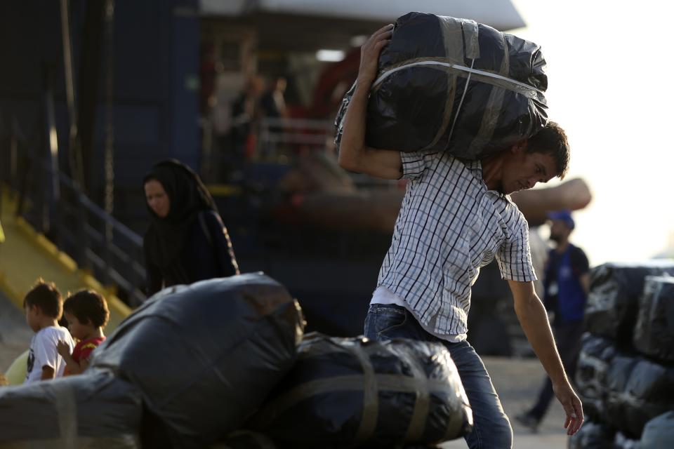 A migrant carries his belongings as he arrives at the port of Thessaloniki, northern Greece, Monday, Sept. 2, 2019. About 1,500 asylum-seekers were being transported from Greece's eastern Aegean island of Lesbos to the mainland Monday as part of government efforts to tackle massive overcrowding in refugee camps and a recent spike in the number of people arriving from the nearby Turkish coast. (AP Photo/Giannis Papanikos)