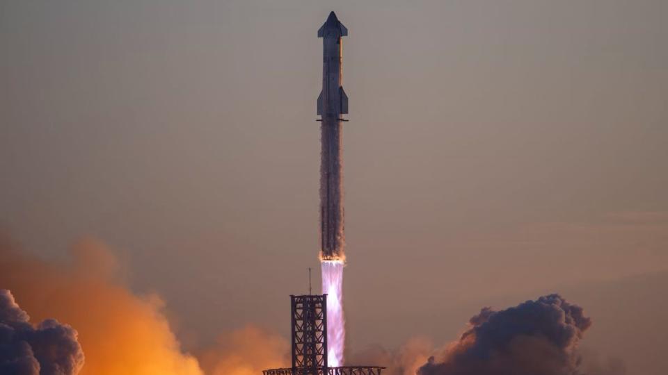 a massive rocket lifts off above a plume of fire