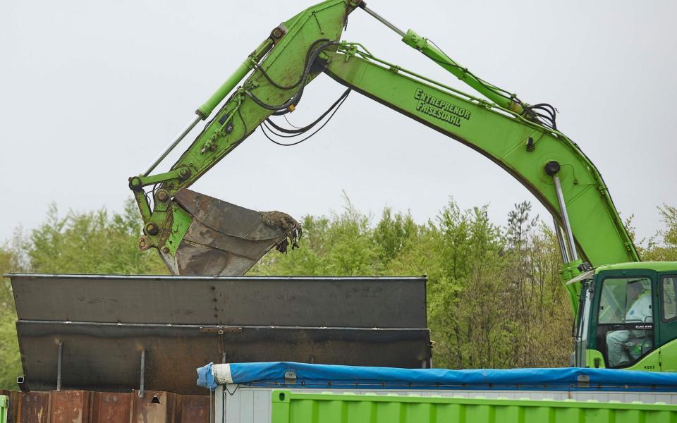 A excavator loads in a container buried mink for incineration during a trial excavation at a military area close to Norre Felding, Holstebro,  - AFP