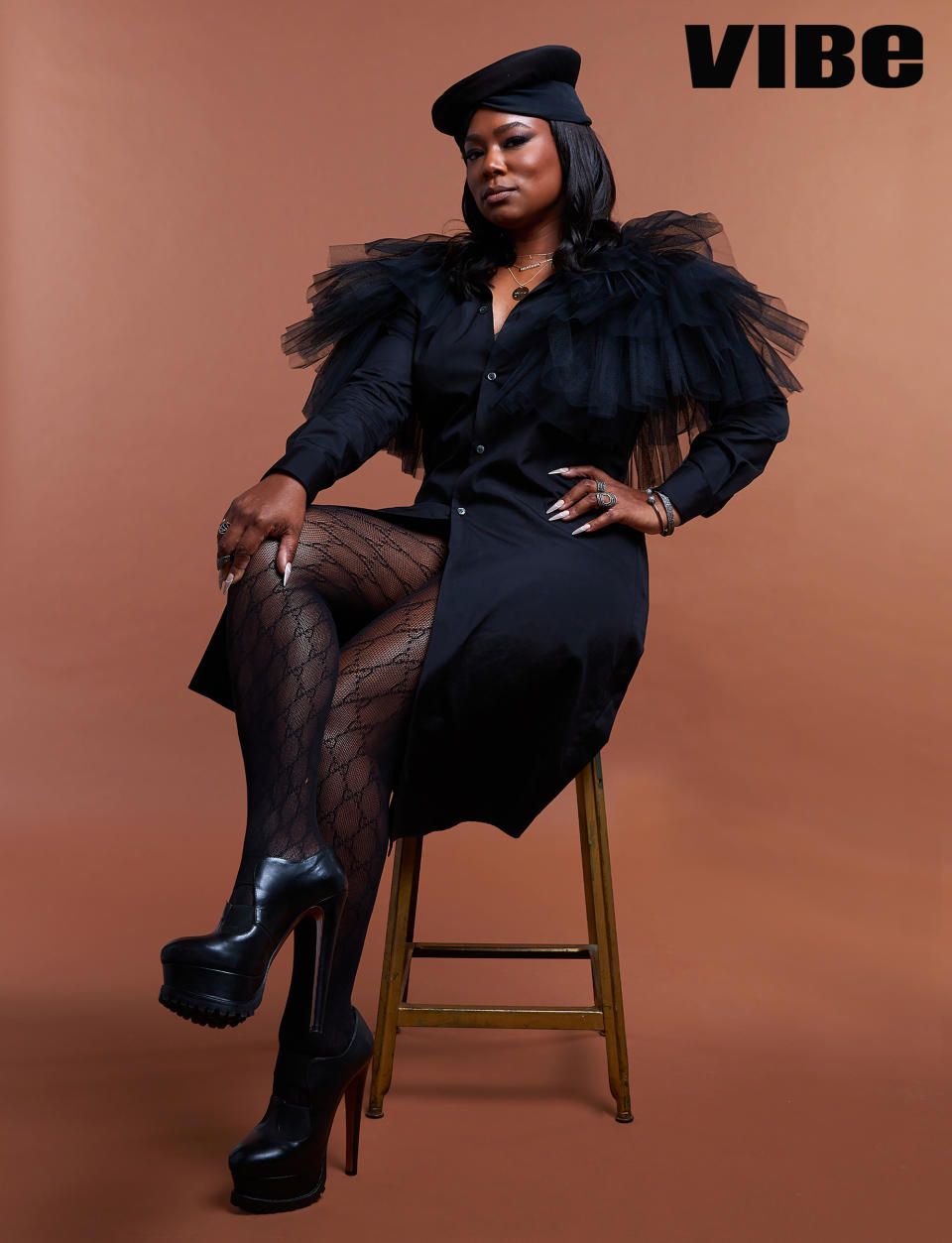 Femme It Forward CEO, Heather Lowery sits proudly in all black dress on a stool, against a mocha colored back drop.